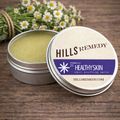 Hills Remedy Healthyskin skin soothing salve with open lid on a wooden surface