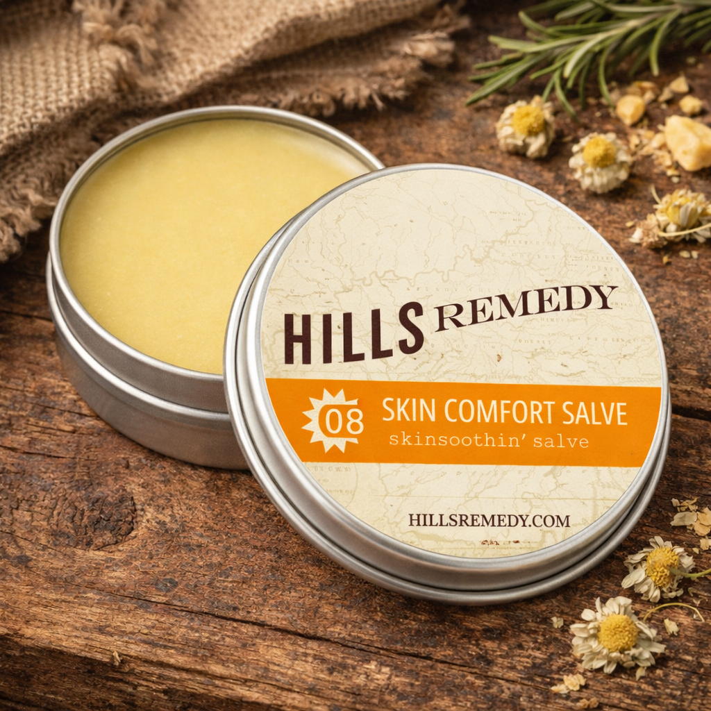 Hills Remedy skin comfort salve in a metal tin on a wooden surface with flowers.