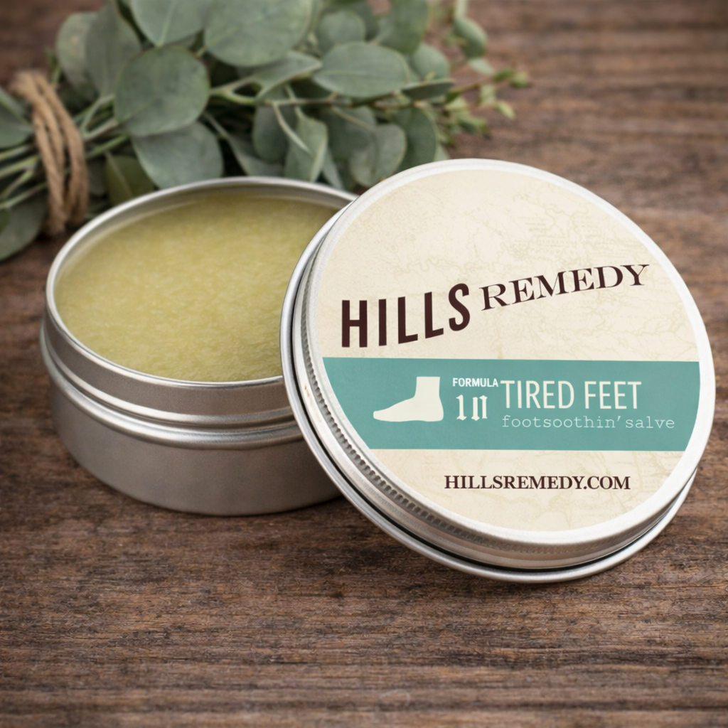 Open tin of Hills Remedy foot soothing salve with a plant in the background on a wooden surface