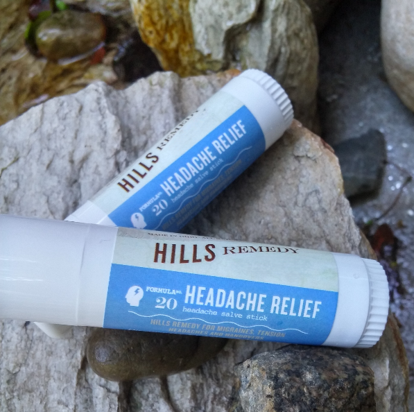 Two 'Hills Remedy' headache relief sticks on a stone surface.